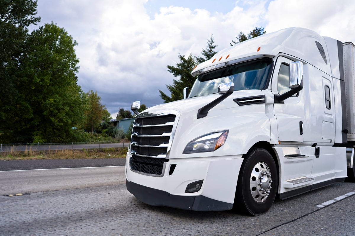 Comfortable white modern big rig semi truck running on divided highway